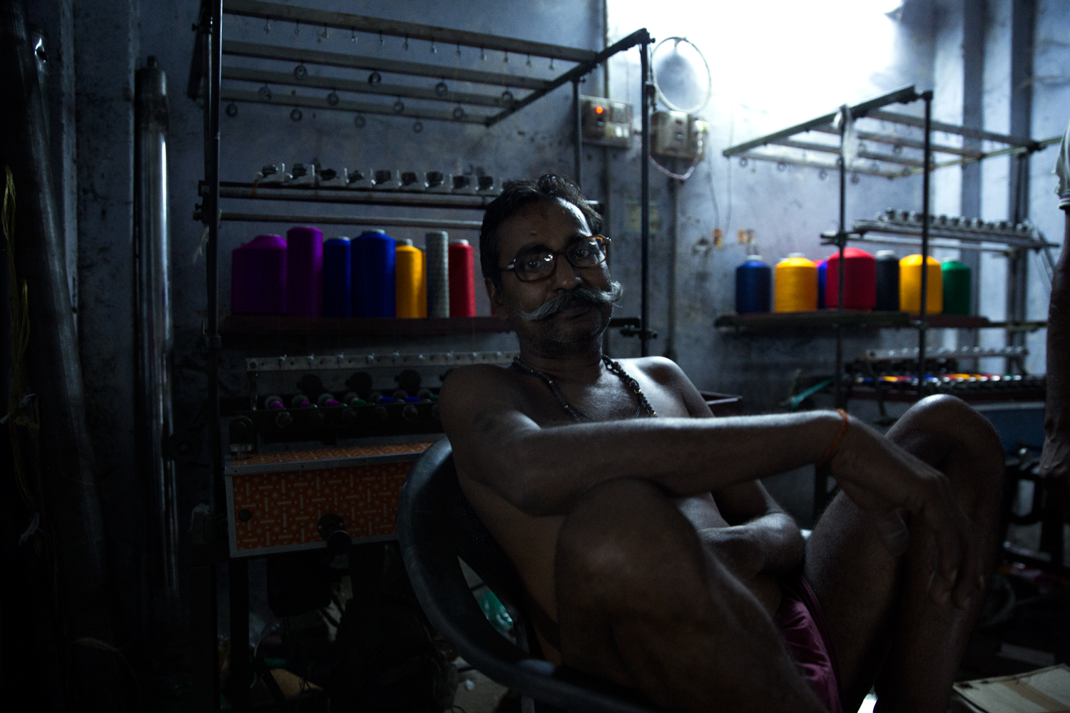 Portrait of an indian weaver sitting in a chair in a dark room