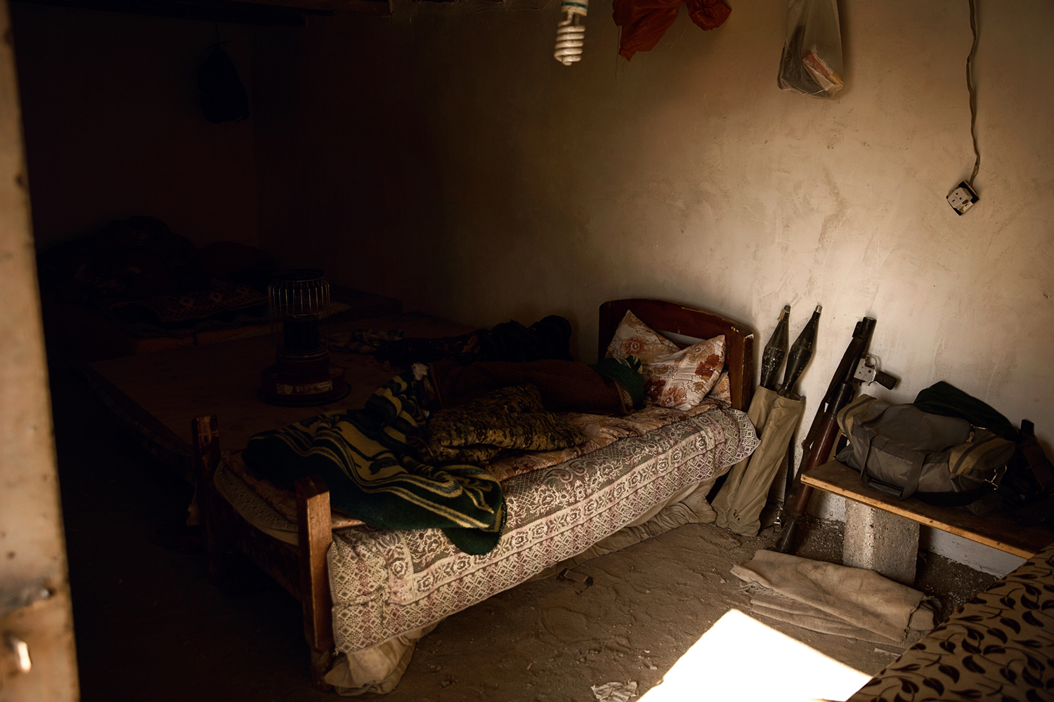 A Peshmerga soldiers bedroom with weapons next to it on the frontline