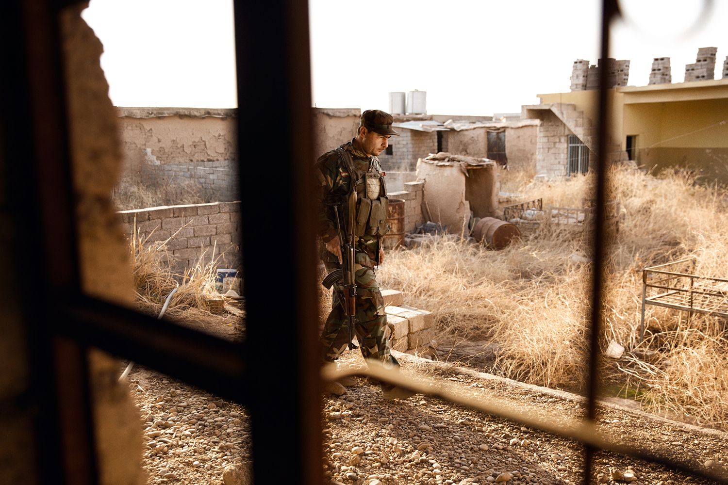 A Peshmerga fighter with his weapon in the ruins of a kurdish town