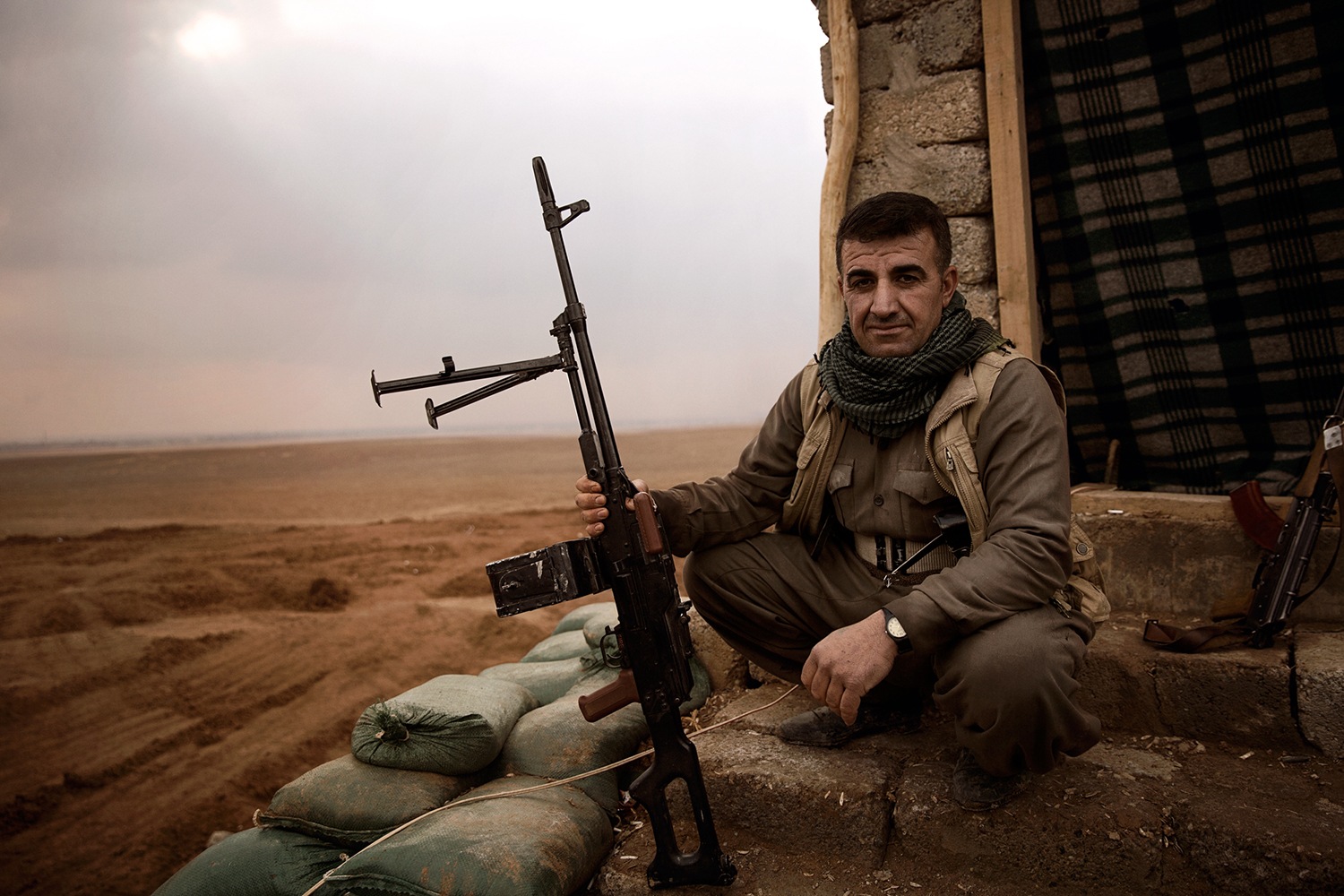 A kurdish Peshmerga fighter with his weapon in front of the Iraqi border